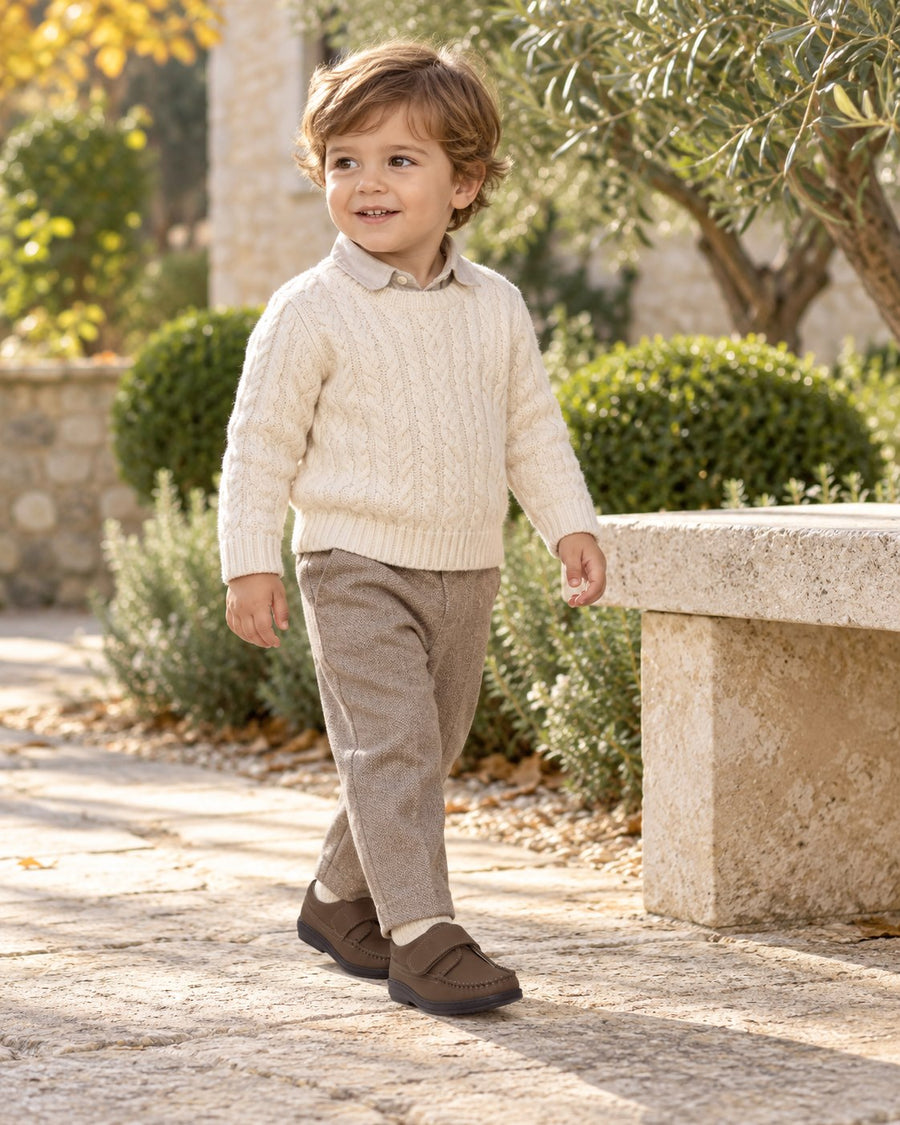 Toddler in an ivory sweater and tailored trousers wearing London Kids brown strap shoes.